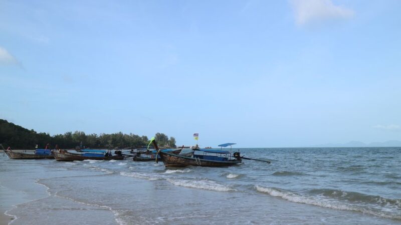 Traditional fishing boats anchored on a serene beach under a clear blue sky.